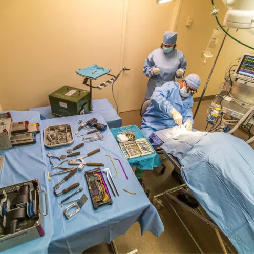 Surgical tools next to an operating table with two staff members